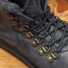 Close-up of Stone color high-top boot with gold accents on a wooden surface