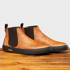 Pair of Brown leather Chelsea boot with black sole on a wooden surface