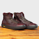 Pair of Dark Brown leather high-top sneaker with a zipper on a wooden surface