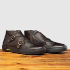 Pair of Brown leather boot with buckles on a wooden surface