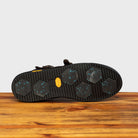 Outsole of Brown leather boot with buckles on a wooden surface