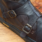 Close view of Brown leather boot with buckles on a wooden surface