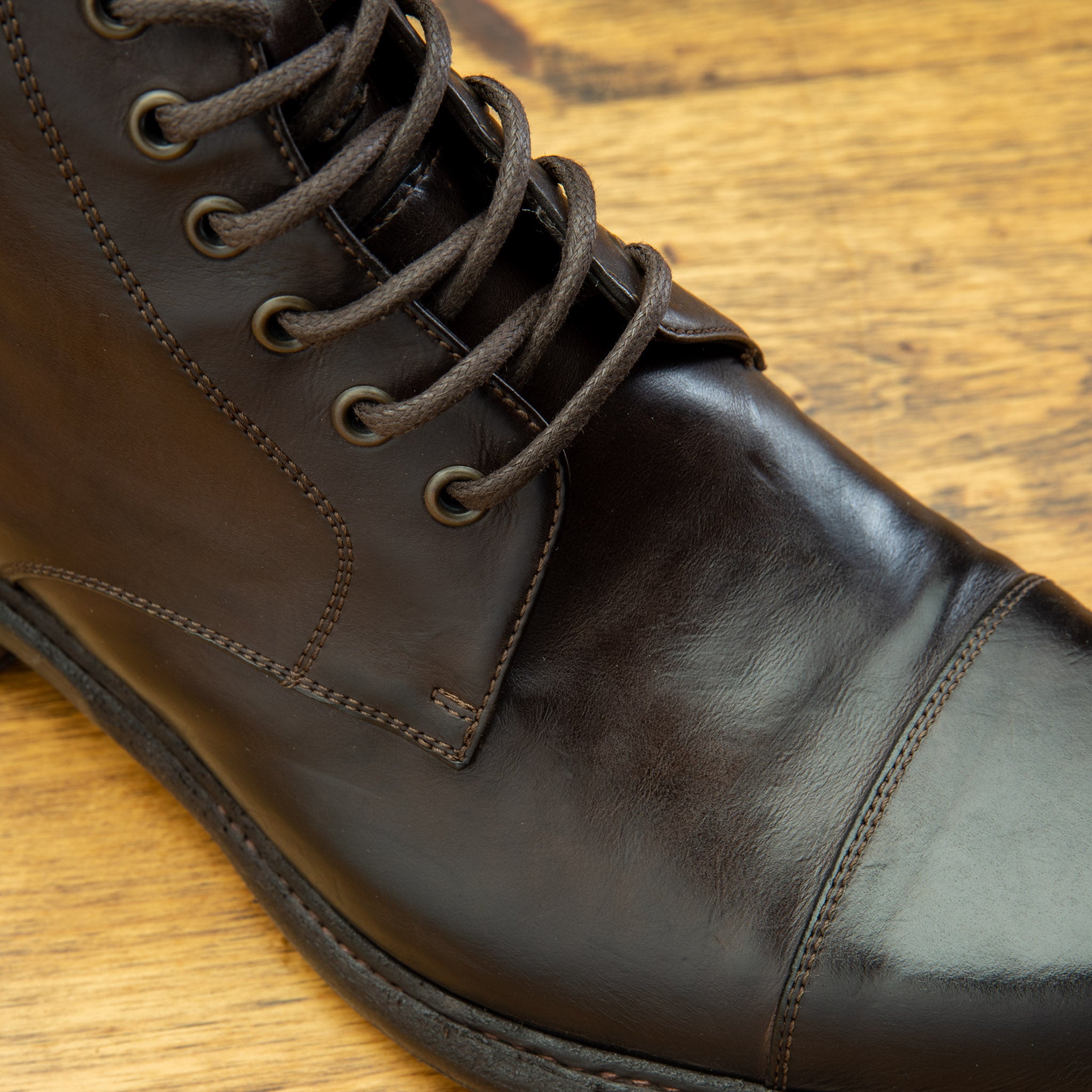 Close view of Brown leather boot on a wooden surface