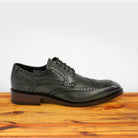 Emerald Green leather dress shoe on a wooden surface with a light gray background