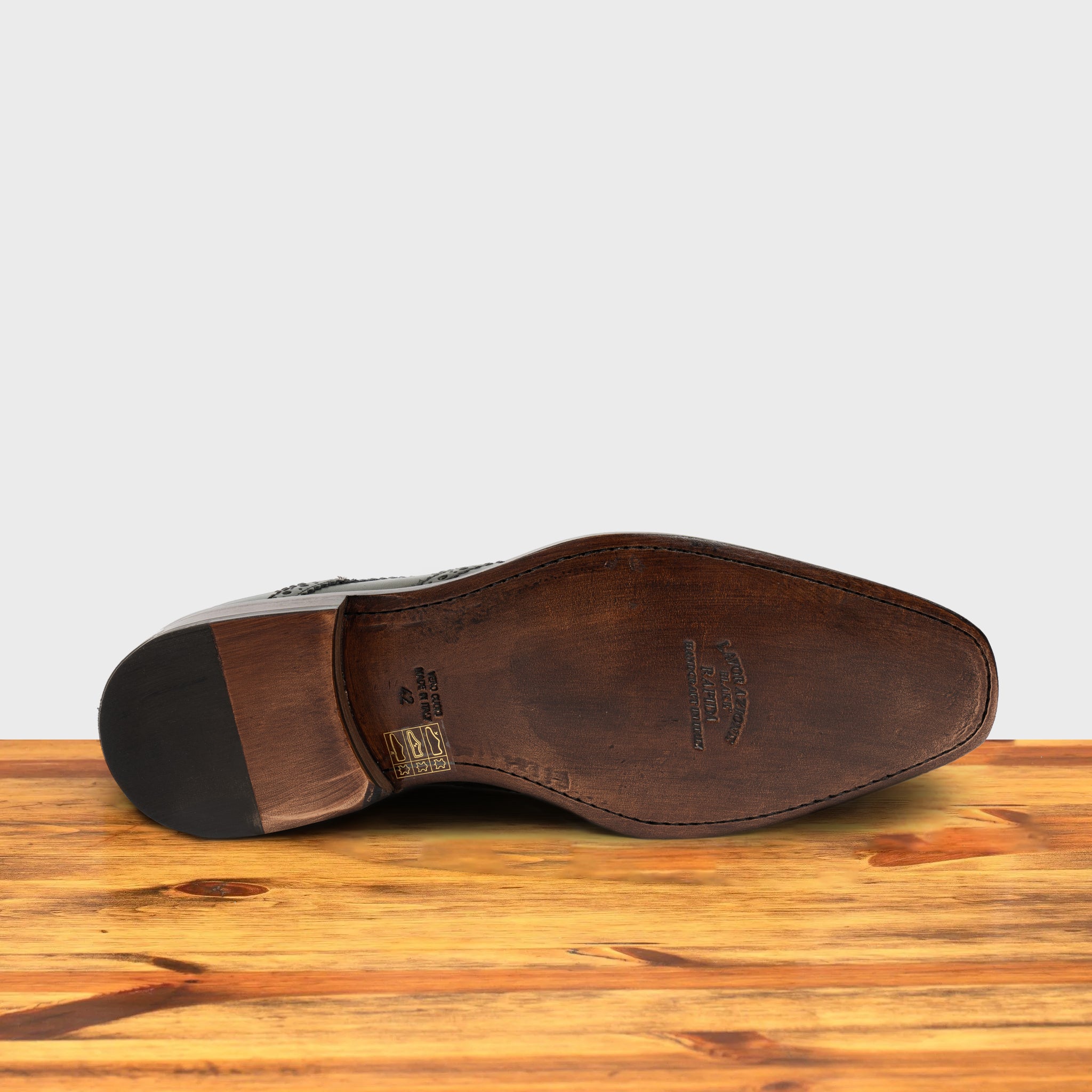 Outsole of Emerald Green leather dress shoe on a wooden surface with a light gray background