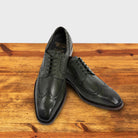 Emerald Green leather dress shoe on a wooden surface with a light gray background