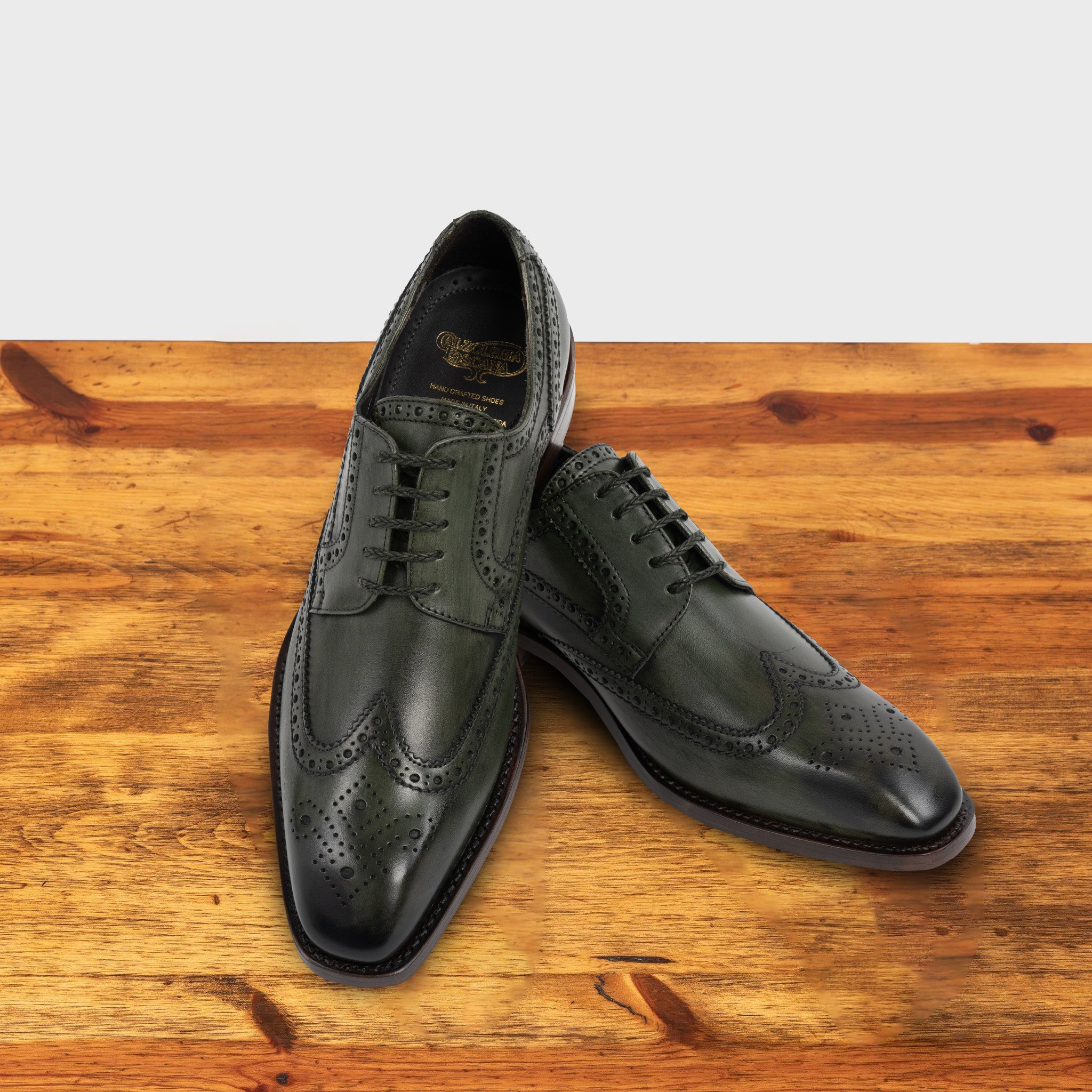 Emerald Green leather dress shoe on a wooden surface with a light gray background