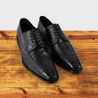 A Pair of Black dress shoe on a wooden surface with a light gray background