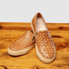 Pair of woven brown slip-on shoes on a wooden surface