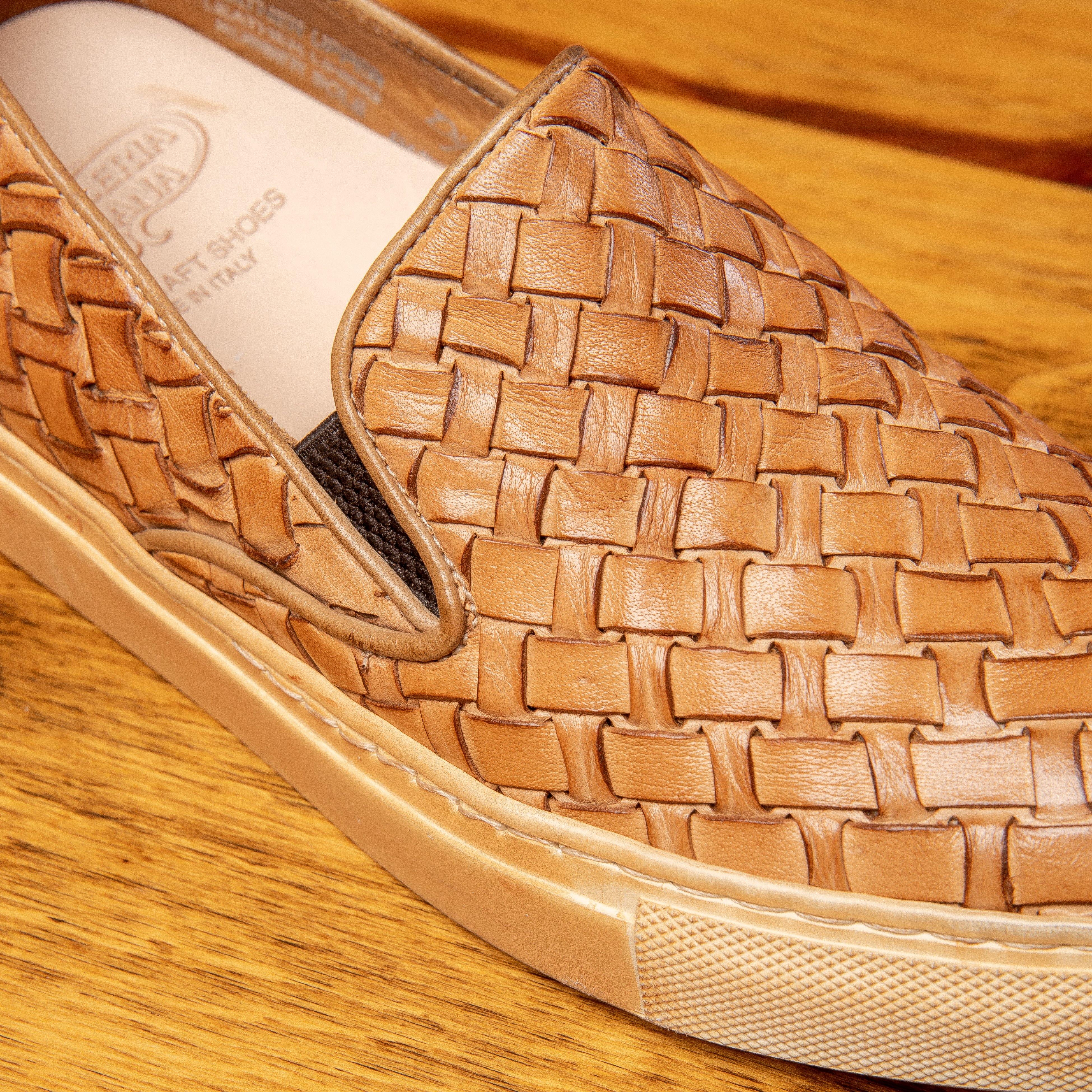 Close view of woven brown slip-on shoes on a wooden surface