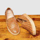 Pair of woven brown slip-on shoes on a wooden surface