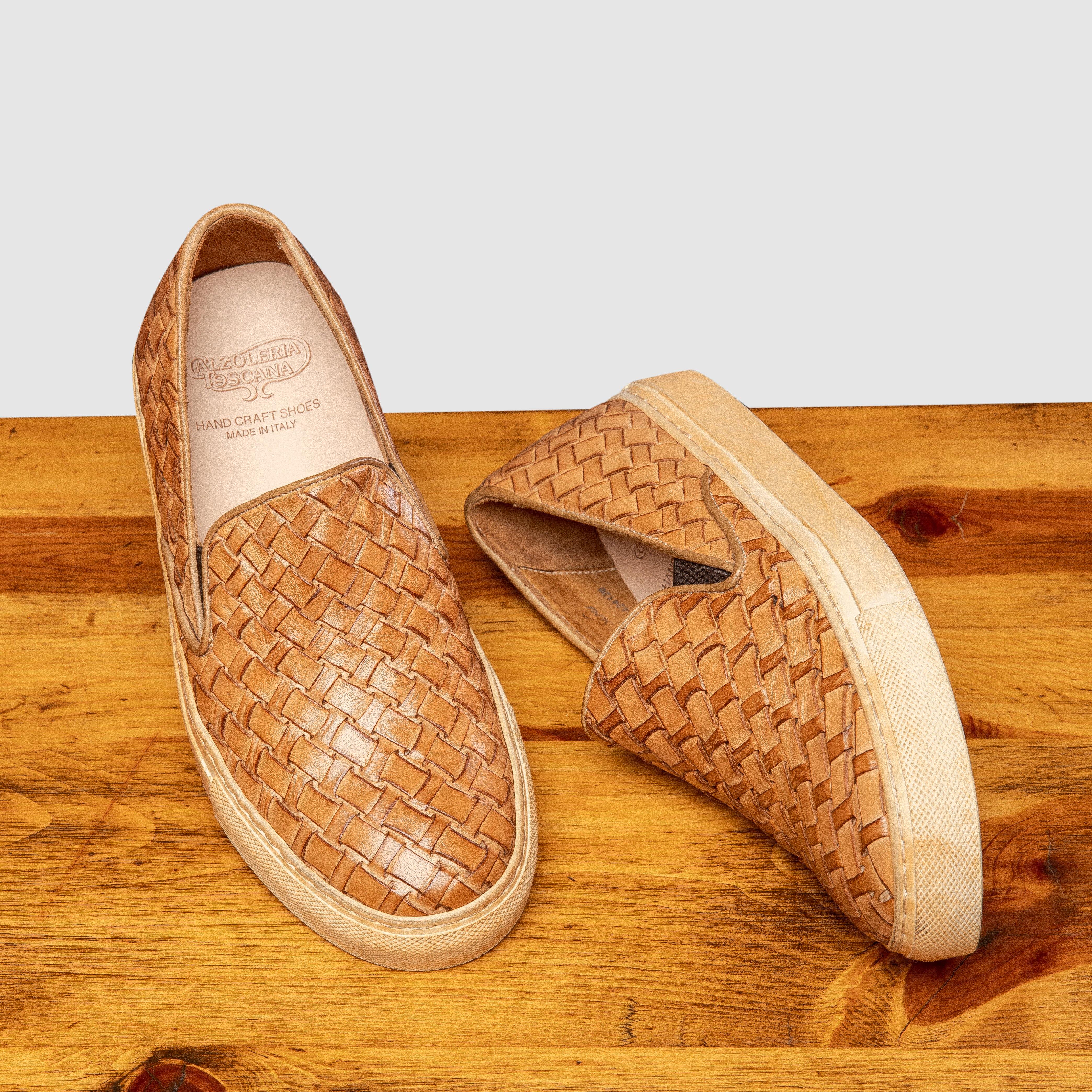 Pair of woven brown slip-on shoes on a wooden surface