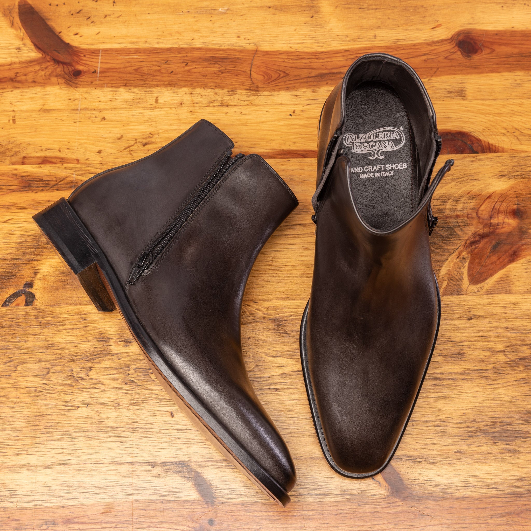 Pair of Dark brown leather ankle boot with zipper on a wooden surface 