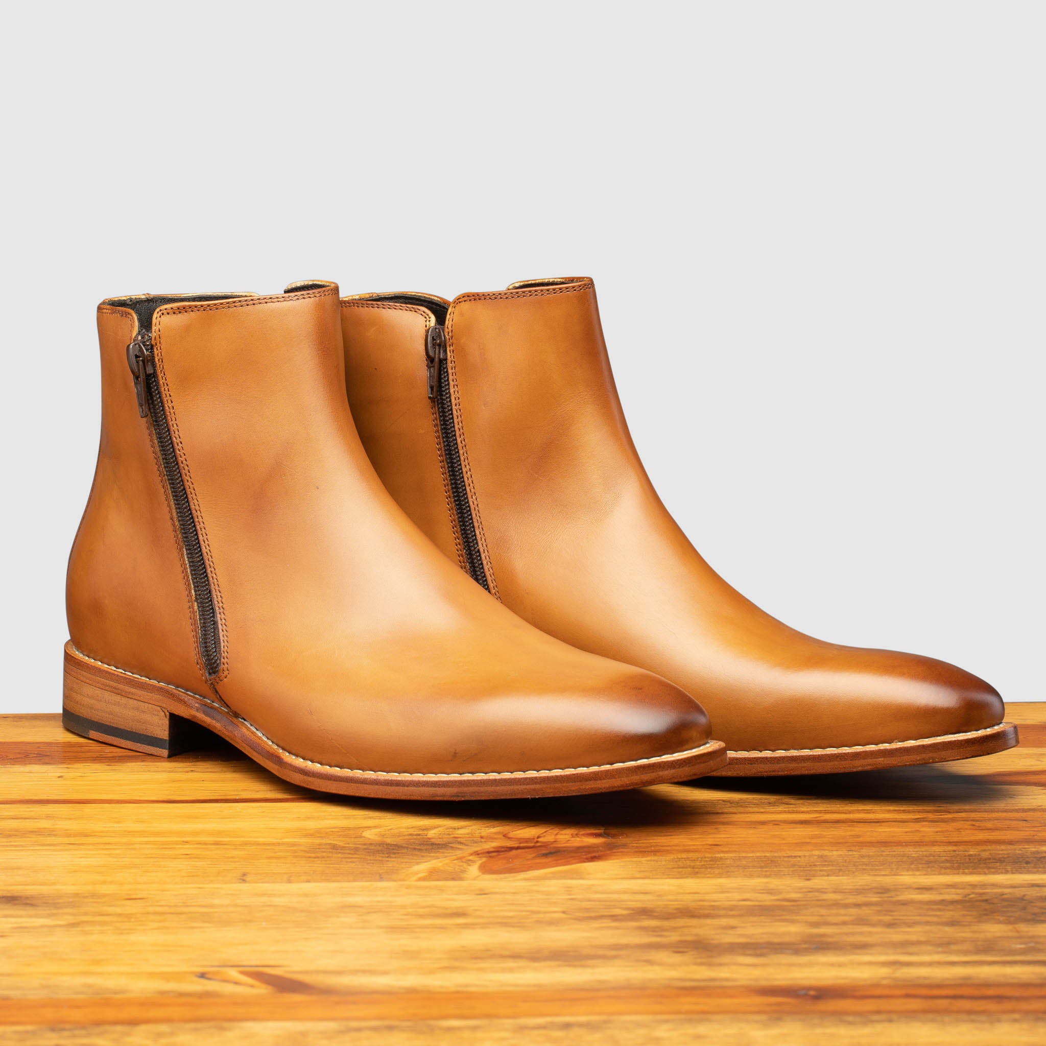 A Pair of chester leather ankle boot with zipper on a wooden surface