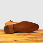 Outsole of chester leather ankle boot with zipper on a wooden surface