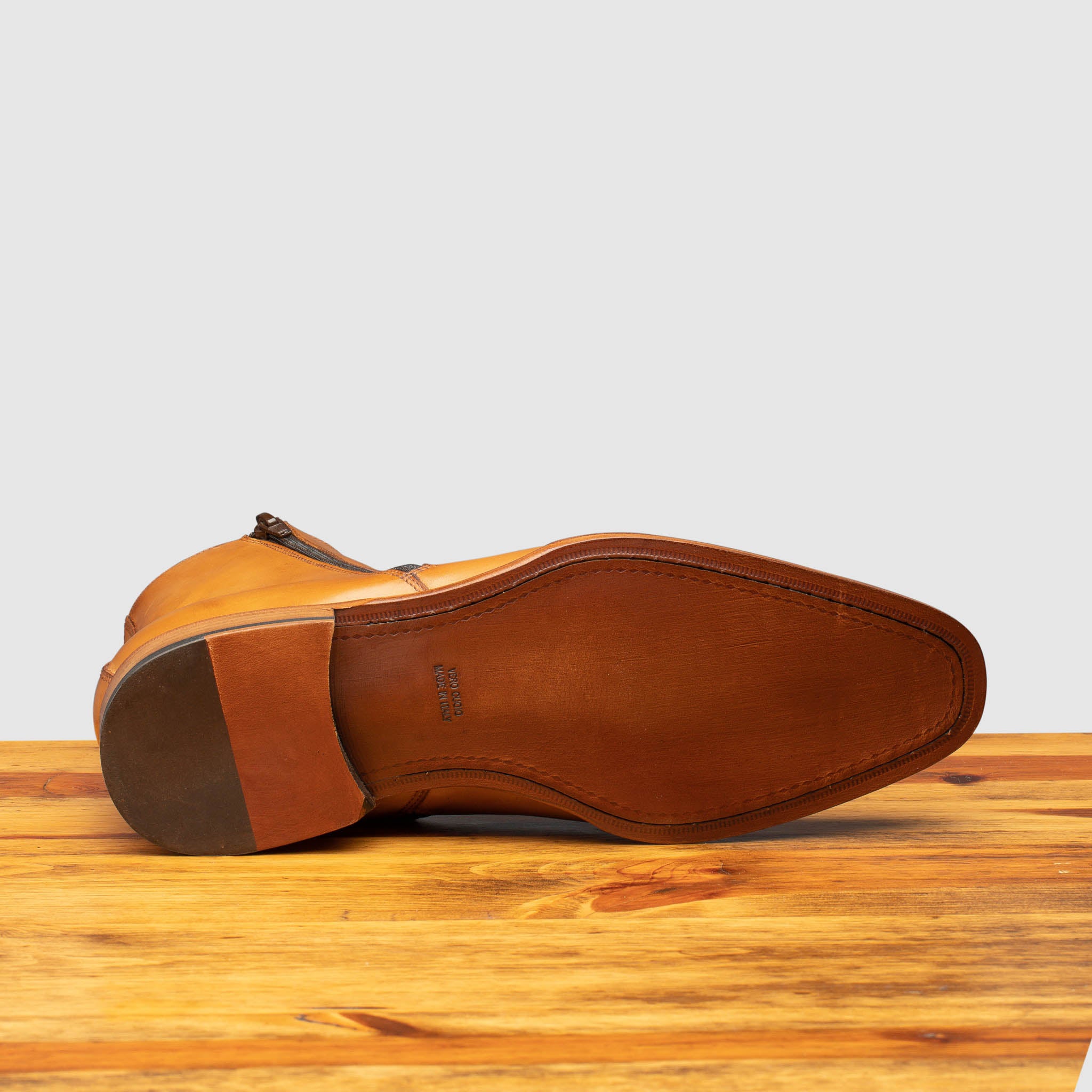 Outsole of chester leather ankle boot with zipper on a wooden surface