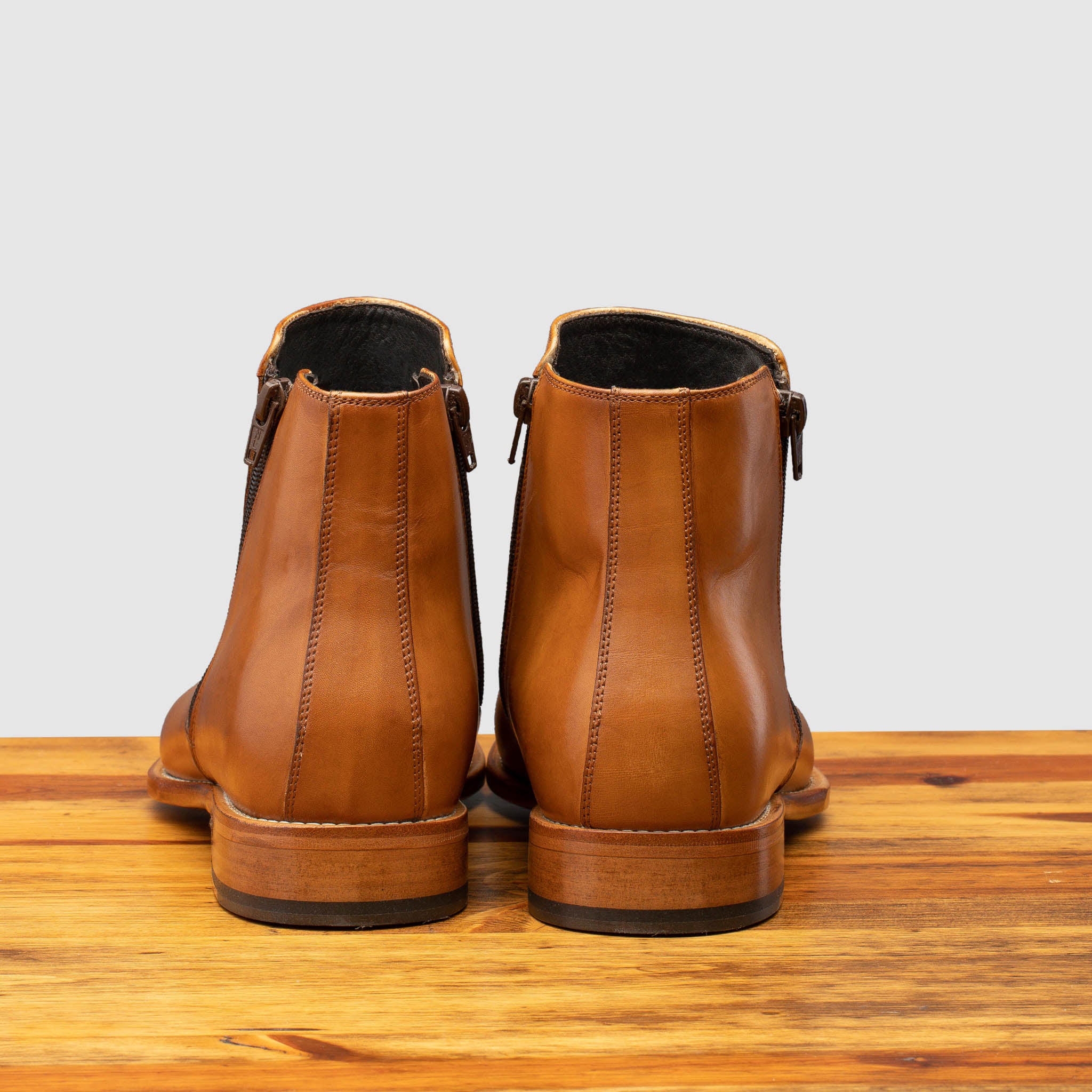 Back view of chester leather ankle boot with zipper on a wooden surface