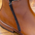 Close-up of chester leather ankle boot with zipper on a wooden surface