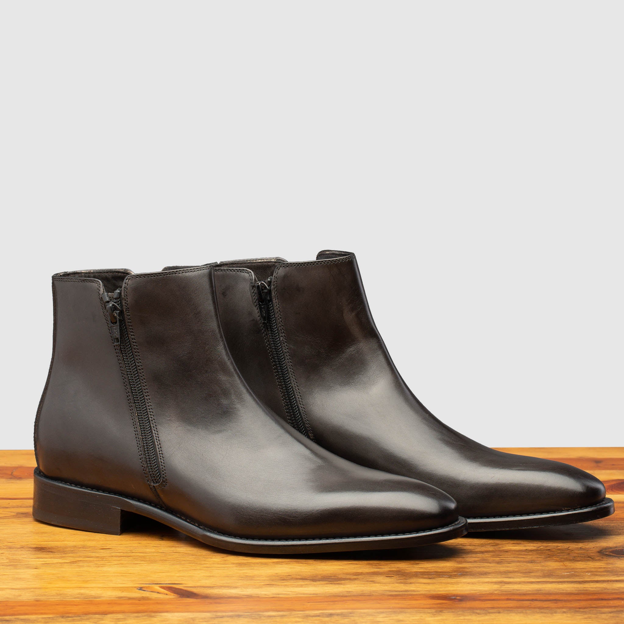 Pair of Dark brown leather ankle boot with zipper on a wooden surface 