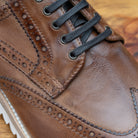 Brown leather shoe on a wooden surface 