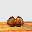 Pair of Brown leather loafer on a wooden surface with a light gray background