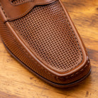 Brown leather loafer on a wooden surface