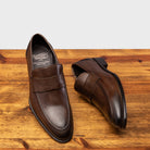 A pair of Moor leather loafer on a wooden surface with a light gray background