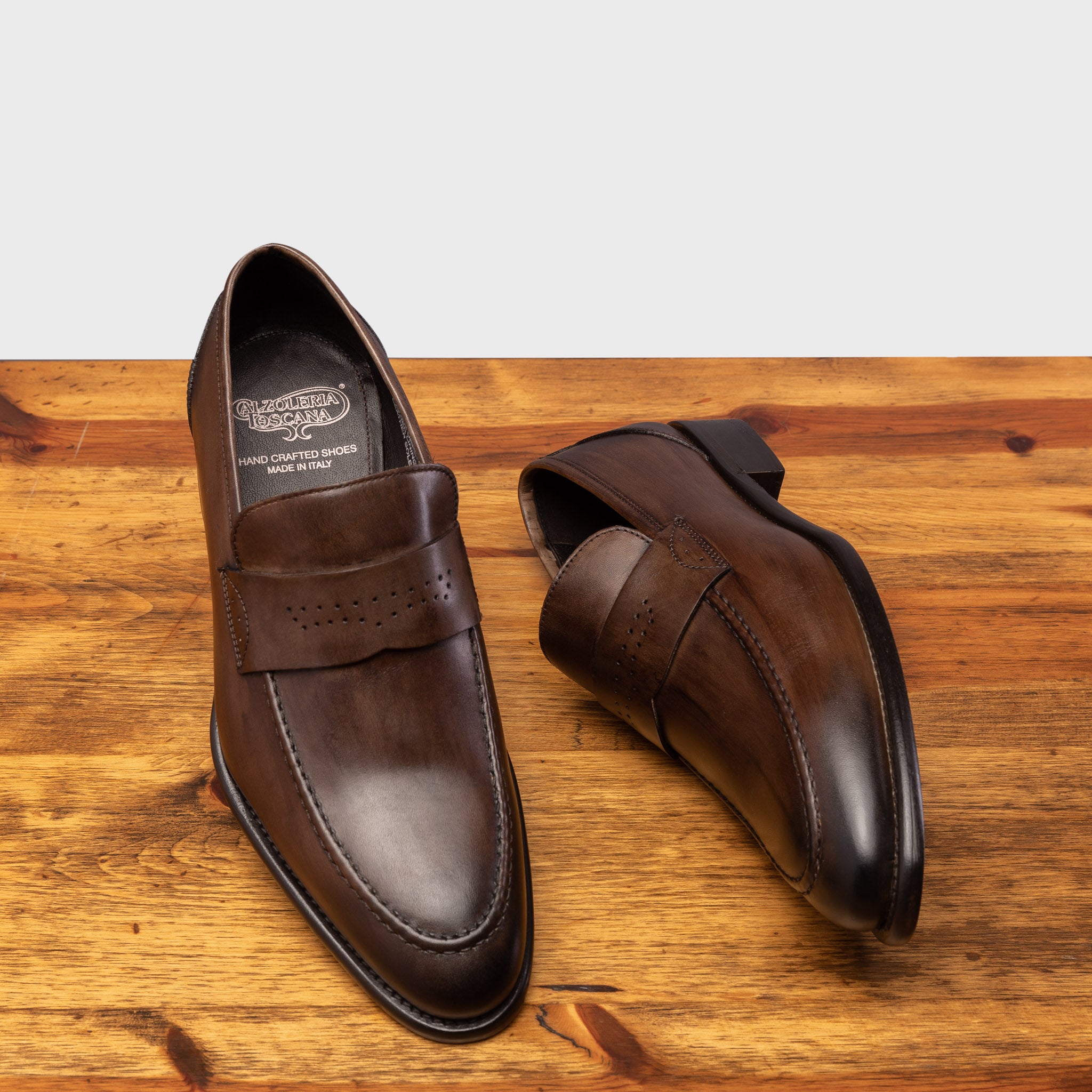 A pair of Moor leather loafer on a wooden surface with a light gray background