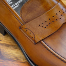 Chestnut leather loafer on a wooden surface