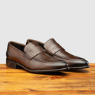 A pair of Moor leather loafer on a wooden surface with a light gray background