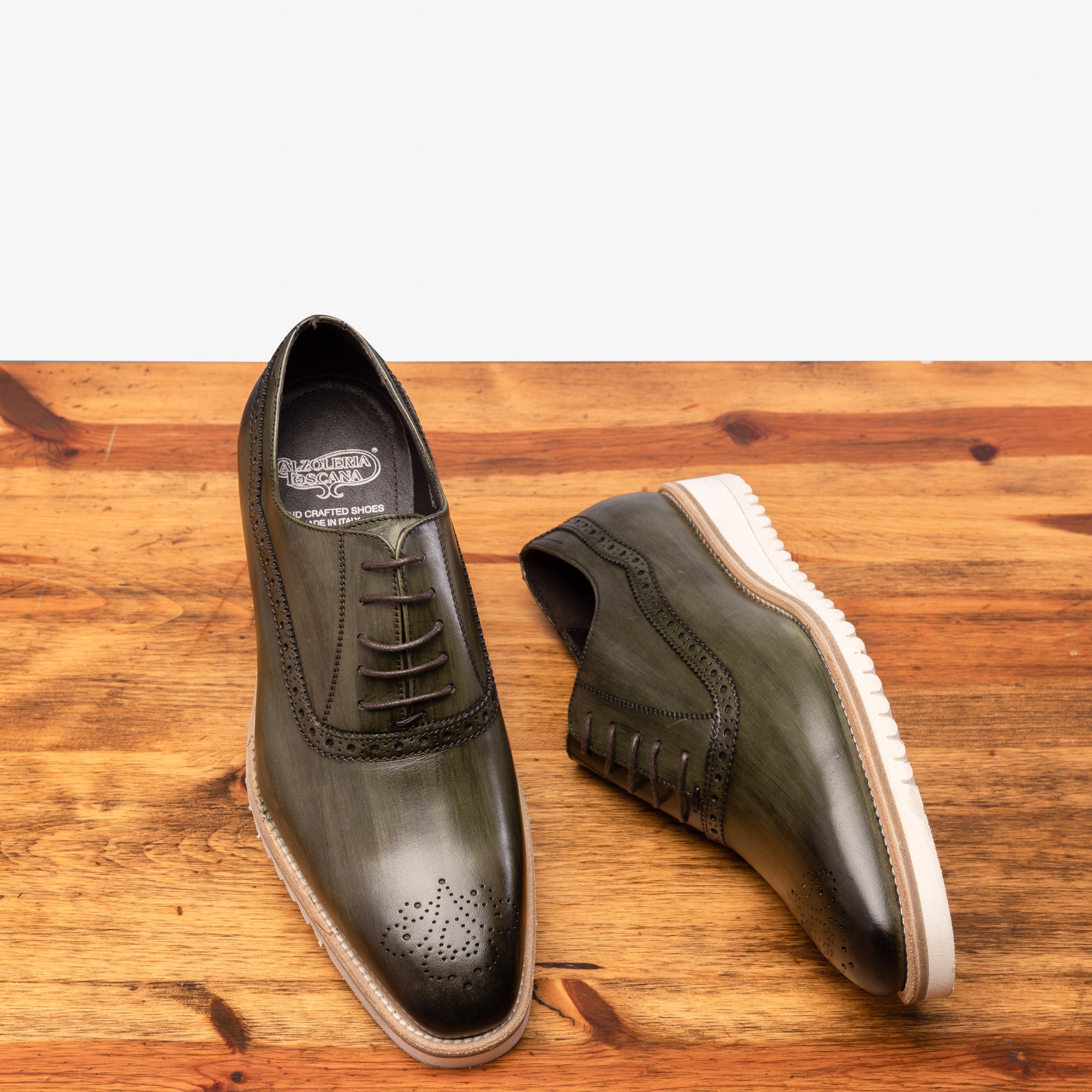 Pair of Green leather shoe on a wooden surface with a gray background