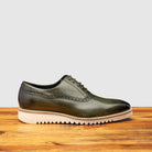 Green leather shoe on a wooden surface with a gray background