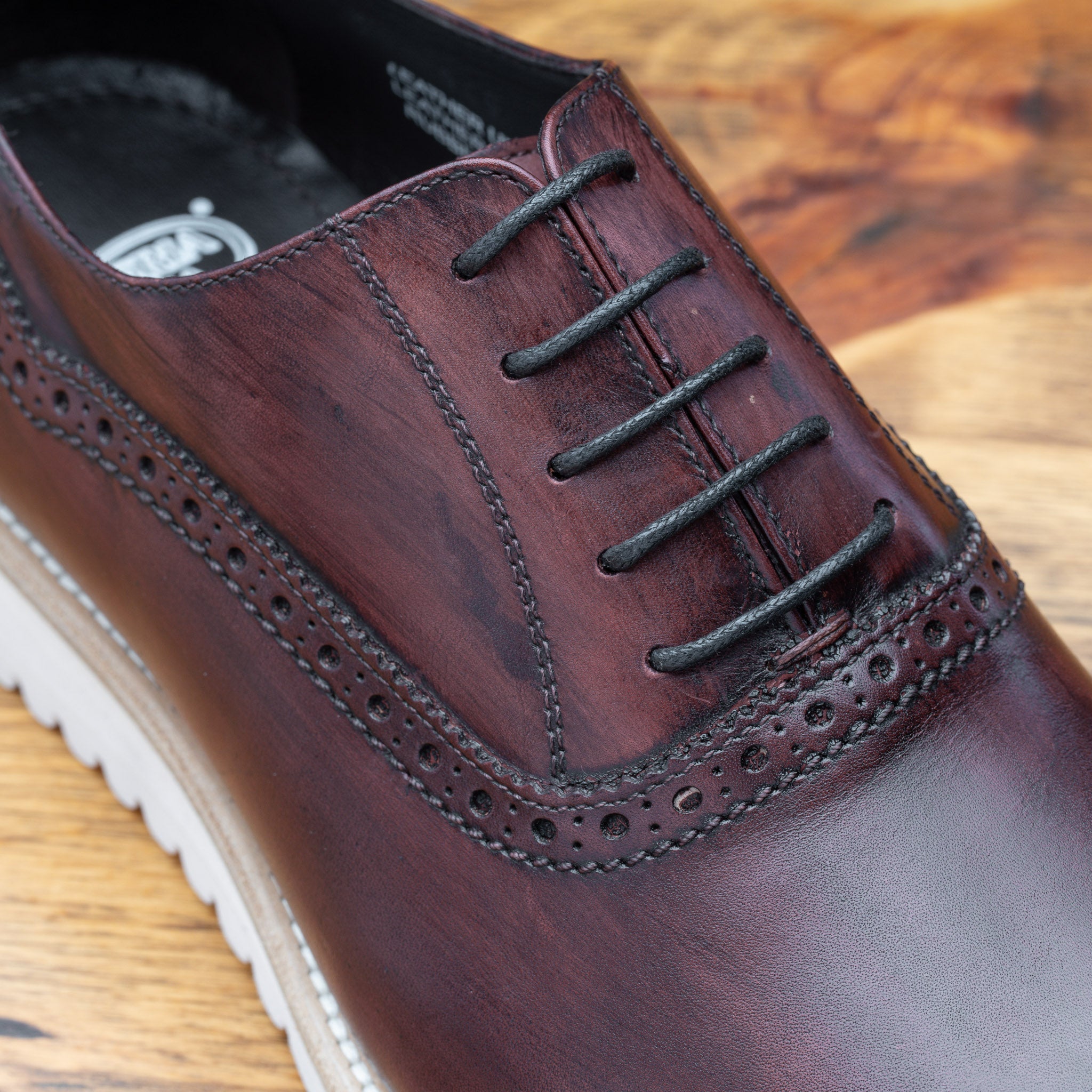 Close-up of Porpora Lace Ups leather shoe on a wooden surface