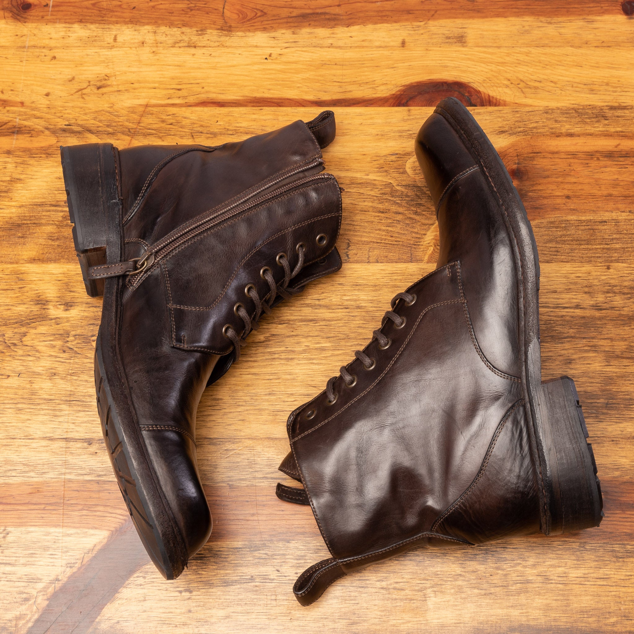 Brown leather boots on a wooden surface with a light gray background