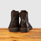 Back view of Brown leather boot on a wooden surface with a light gray background