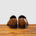 A Pair of chestnut wholecut leather Oxford shoe, displayed on a wooden surface.
