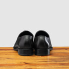 A Pair of Graphite leather dress shoe on a wooden surface with a light gray background