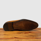 Outsole of chestnut wholecut leather Oxford shoe, displayed on a wooden surface.