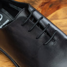 Graphite  leather dress shoe on a wooden surface
