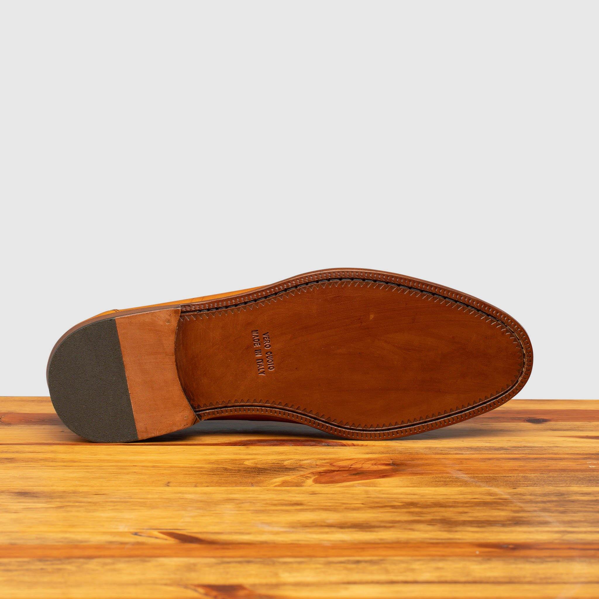 Outsole of Dark Caramel leather loafer on a wooden surface with a light gray background