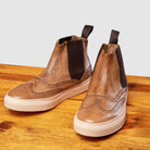Pair of Brown leather shoe on a wooden surface with a light gray background
