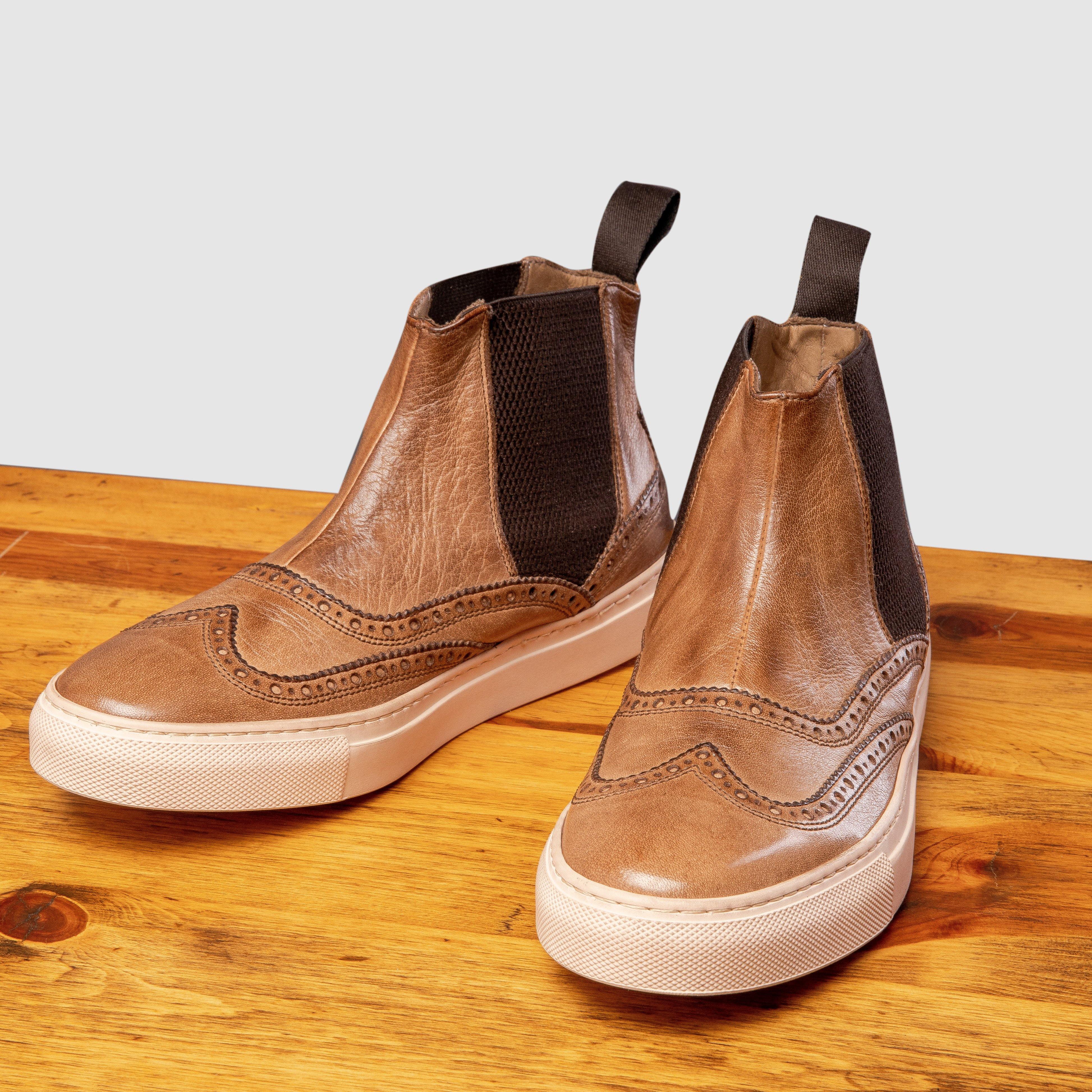 Pair of Brown leather shoe on a wooden surface with a light gray background