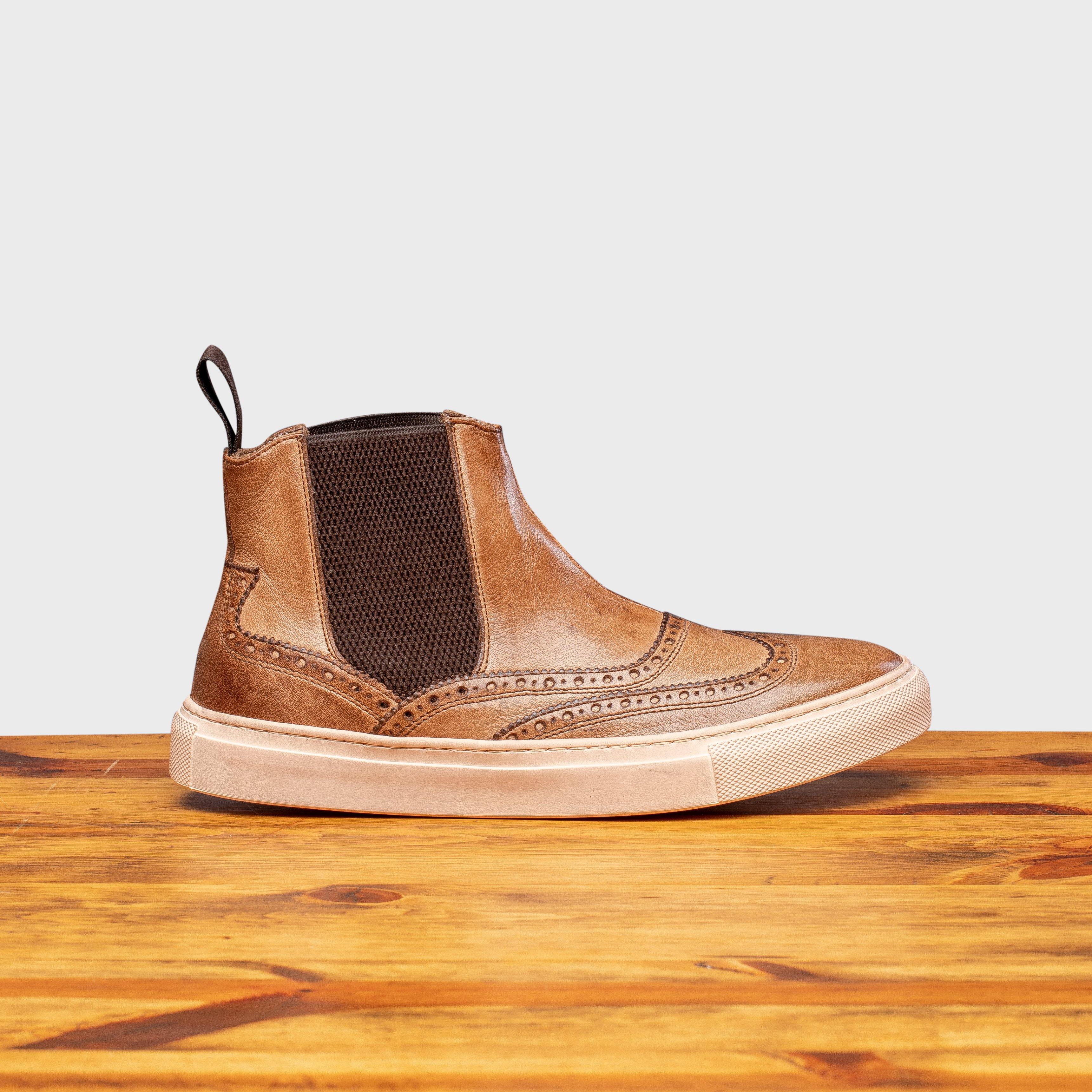 Brown leather shoe on a wooden surface with a light gray background
