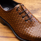 Chestnut woven dress shoe on a wooden surface