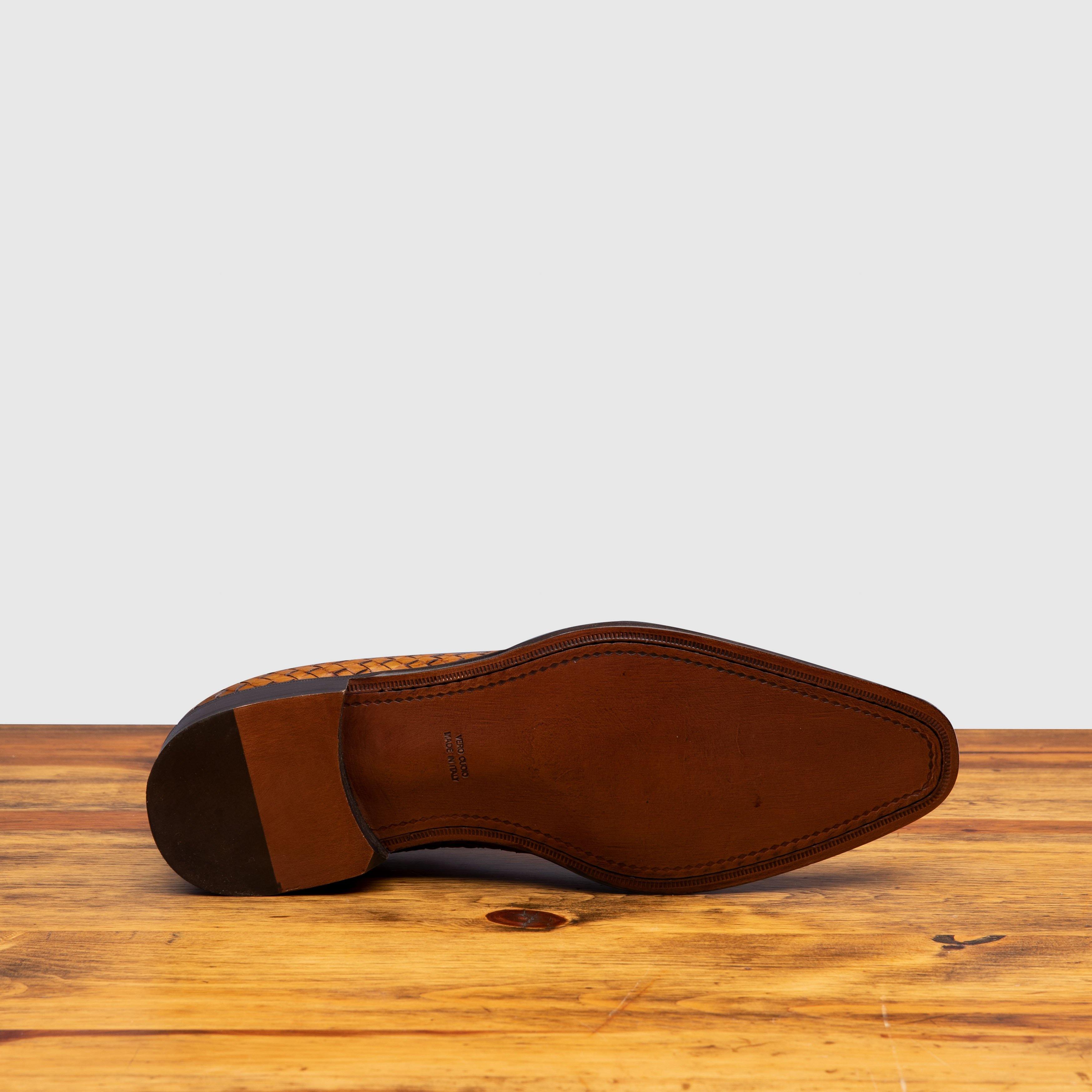 Outsole of Chestnut woven dress shoe on a wooden surface with a light gray background