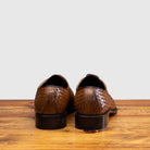 A Pair of Chestnut woven dress shoe on a wooden surface with a light gray background