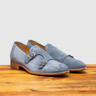 A pair of Blue suede loafer with brown sole on a wooden surface