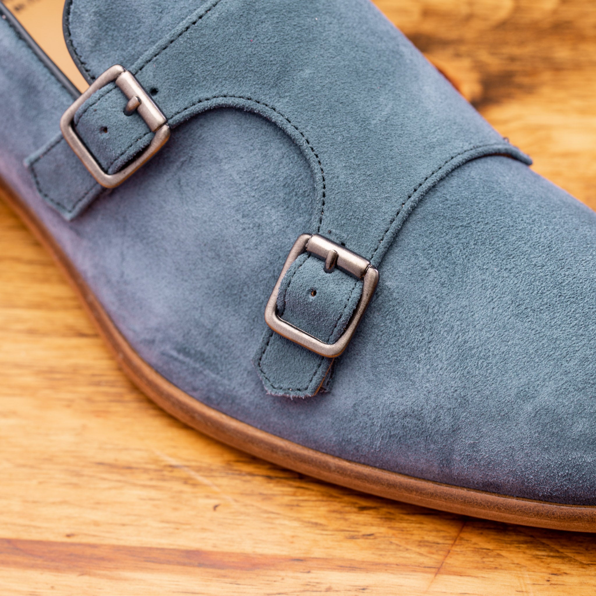 Close view of Blue suede loafer with brown sole on a wooden surface