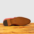 Outsole of Red suede loafer with brown sole on a wooden surface