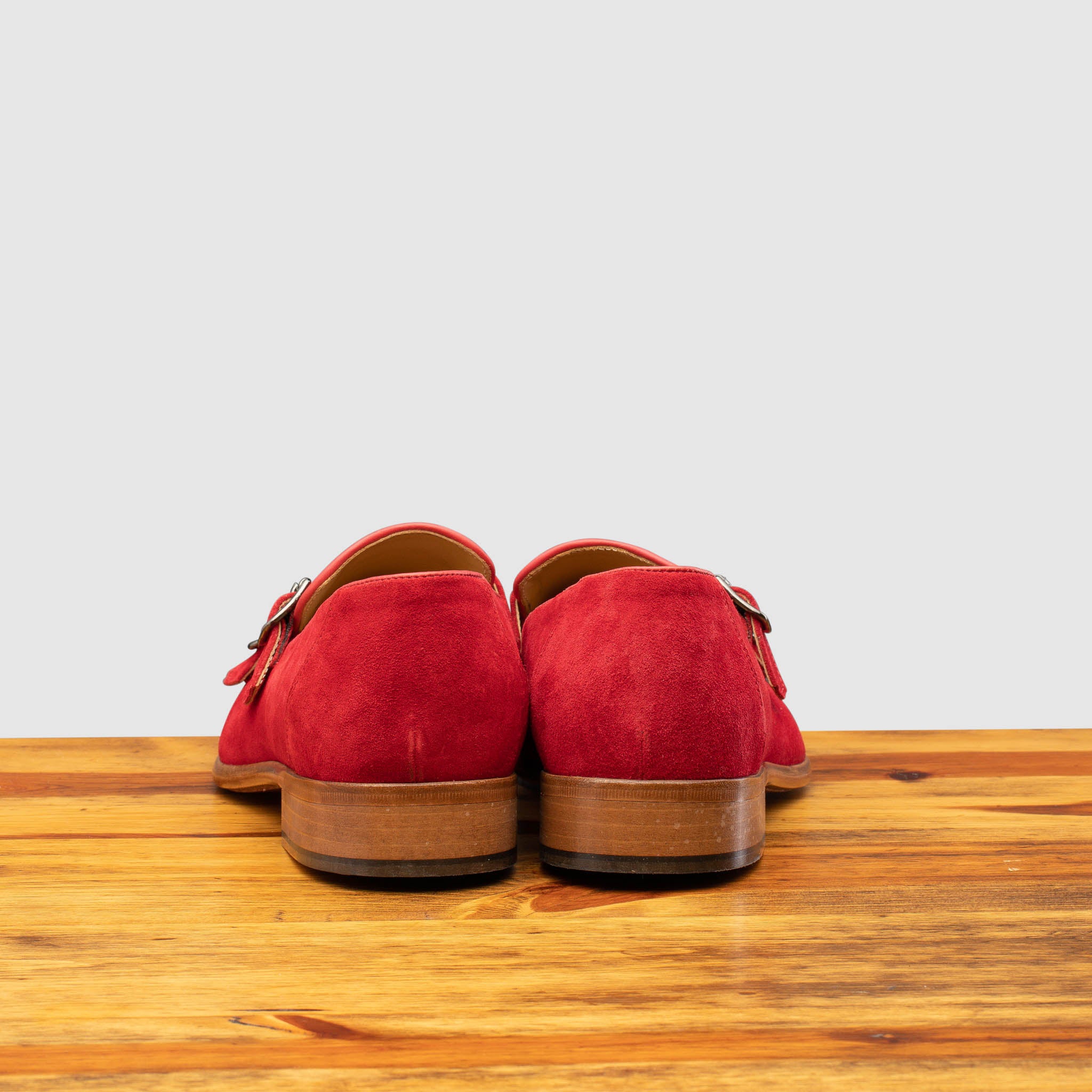 Back view of Red suede loafer with brown sole on a wooden surface